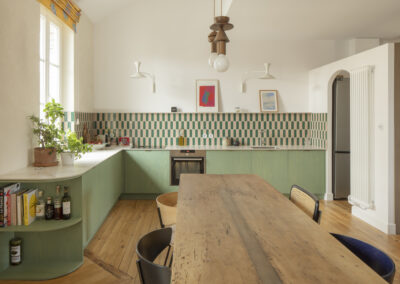 Cuisine aux façades vert céladon et table en bois, appartement à Biarritz